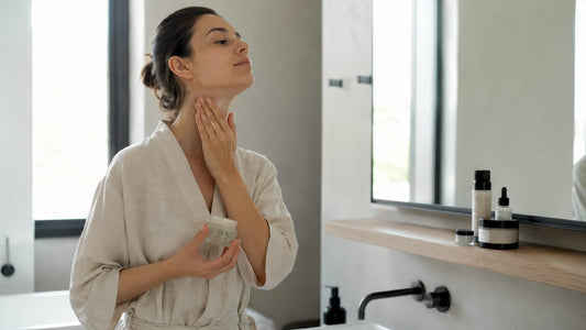 O femeie își masează crema preferată pe gât, relaxându-se acasă.