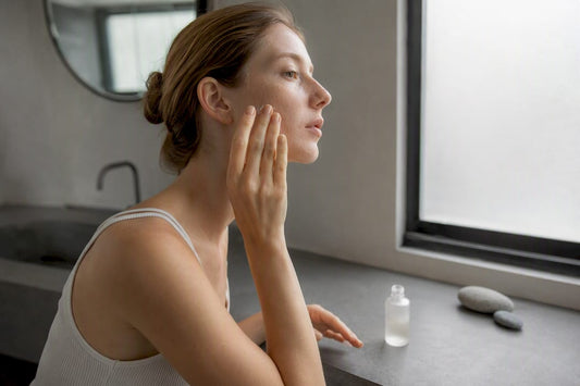 Mâini care aplică ser pentru îngrijirea pielii într-o baie minimalistă